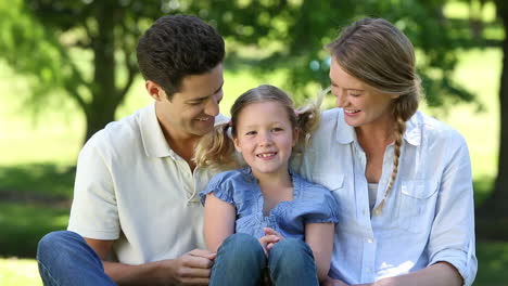 happy parents with their young daughter in the park