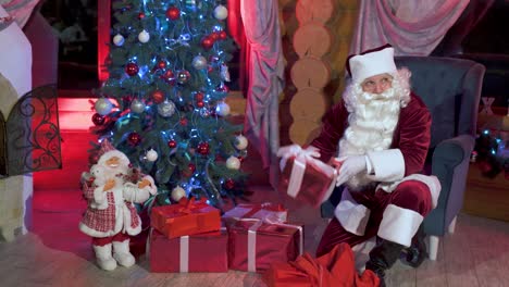 surprise under the christmas tree. santa with christmas presents in the house. old santa taking out gifts from his red bag. christmas atmosphere