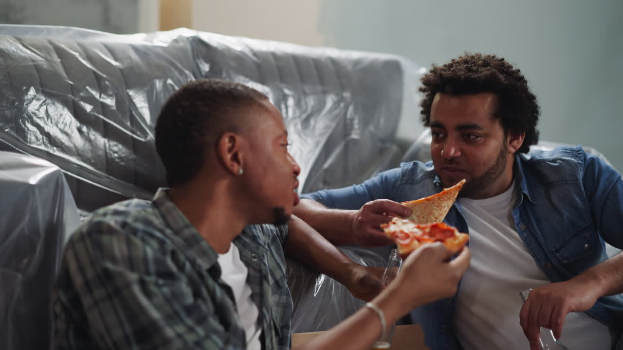 uomo afroamericano allegro mangia pizza e parla con un amico