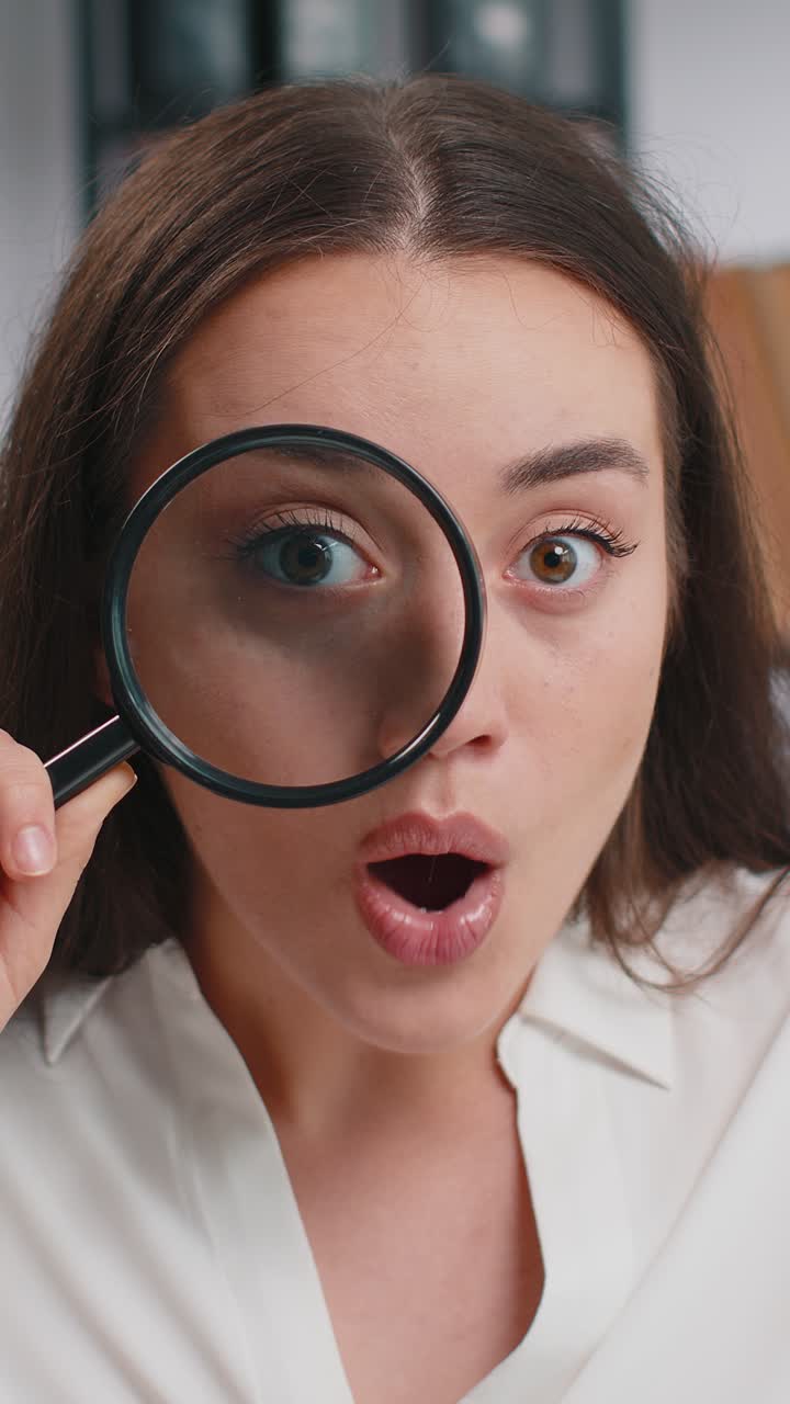 Business woman holding magnifying glass near face looking with big zoomed eye searching analysing