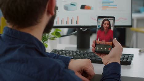 Paralysed-manager-sitting-in-wheelchair-holding-smartphone-for-videocall