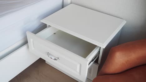 white nightstand with empty drawer and brown chair