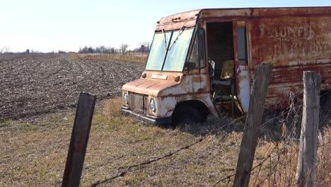 an abandoned delivery truck sits in a plowed field in the midwest