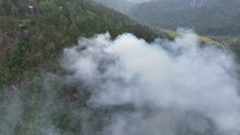 aerial descent into thick smoke from mountain forest fire outside bergen norway