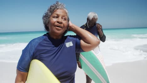 senior couple with surfboards at the beach