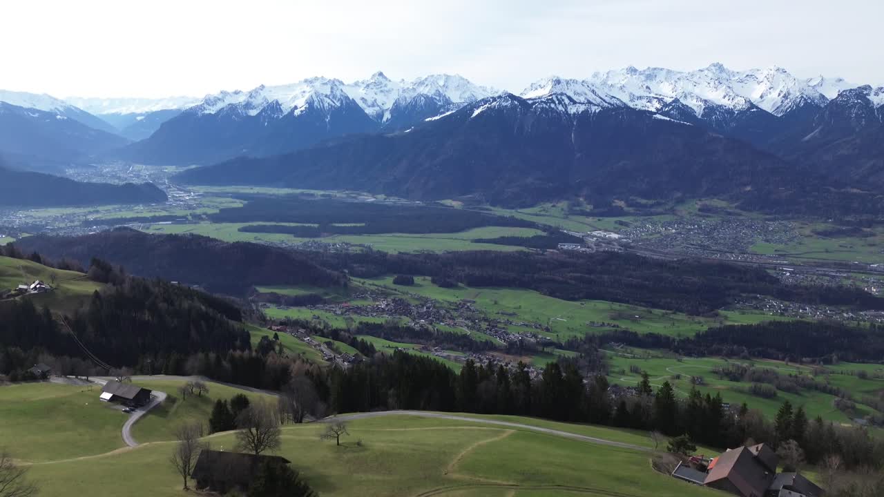 Drone fly above Farm in Austrian Mountains with Snow Covered Summits in Background
