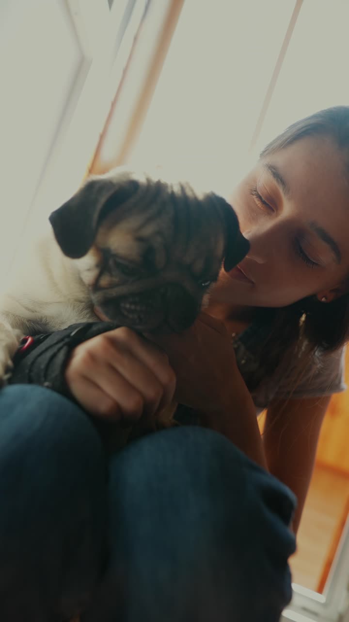 una niña sosteniendo amorosamente a un cachorro de pug