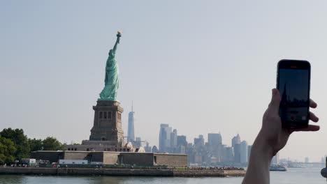 slow motion landscape of person taking mobile smartphone image photo picture of statue of liberty monument in new york city manhattan usa america travel tourism sightseeing