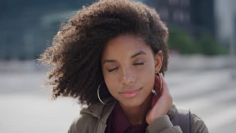 Retrato-Hermosa-Joven-Afroamericana-Sonriendo-Corriendo-De-La-Mano-A-Través-Del-Cabello-Mujer-Negra-Independiente-Disfrutando-De-Un-Estilo-De-Vida-Tranquilo-De-Verano-En-La-Ciudad-Viento-Soplando-Peinado-Afro