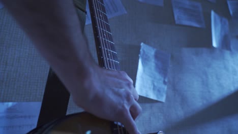 man grabbing acoustic guitar with one hand