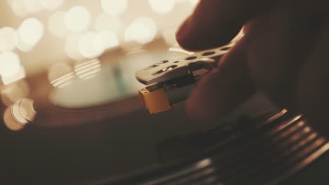 the player vinyl close-up on a background of blurry bright bokeh of lights. rotating plate and stylus with a needle turntable close-up. a man's hand puts the needle on the black vinyl