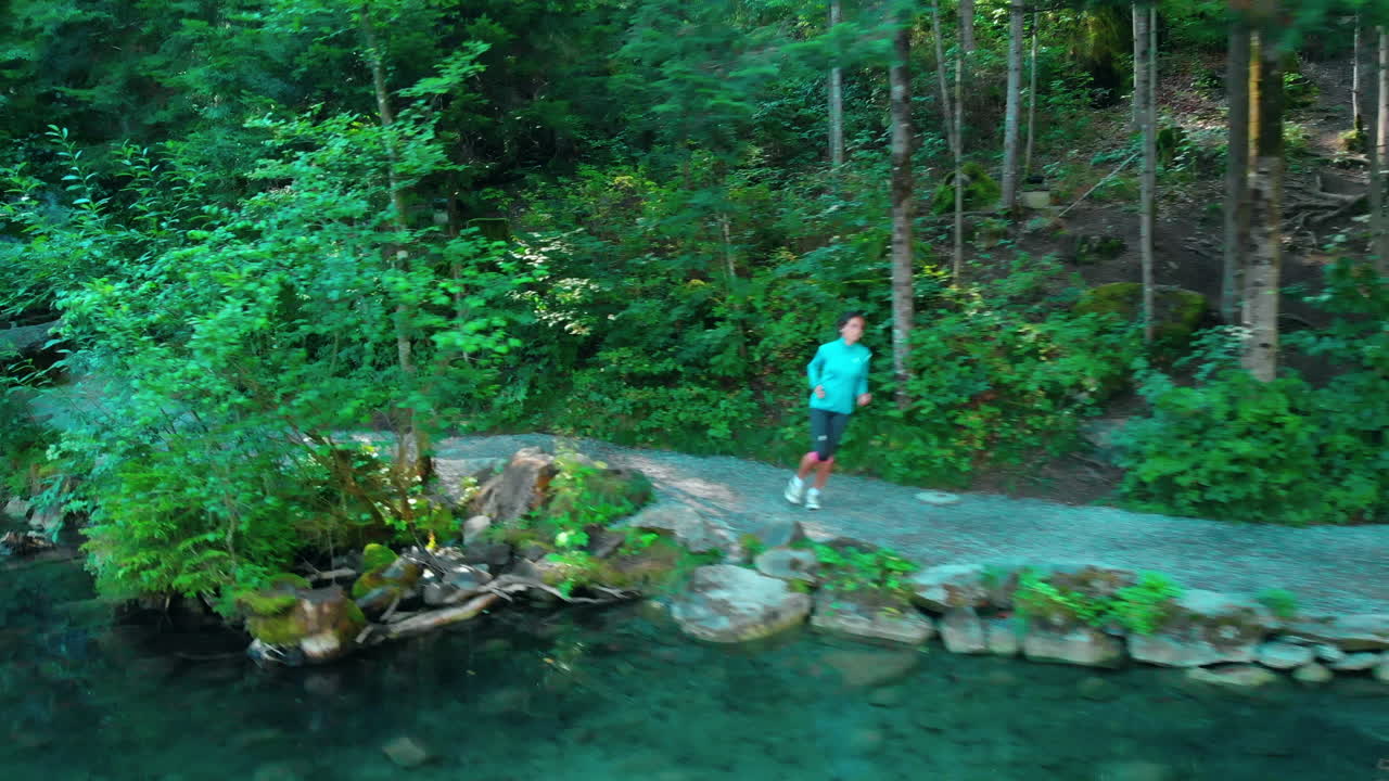 자연의 아름다운 호수 옆에서 달리는 나이든 스포티한 여성의 옆에서 드론을 쏘다