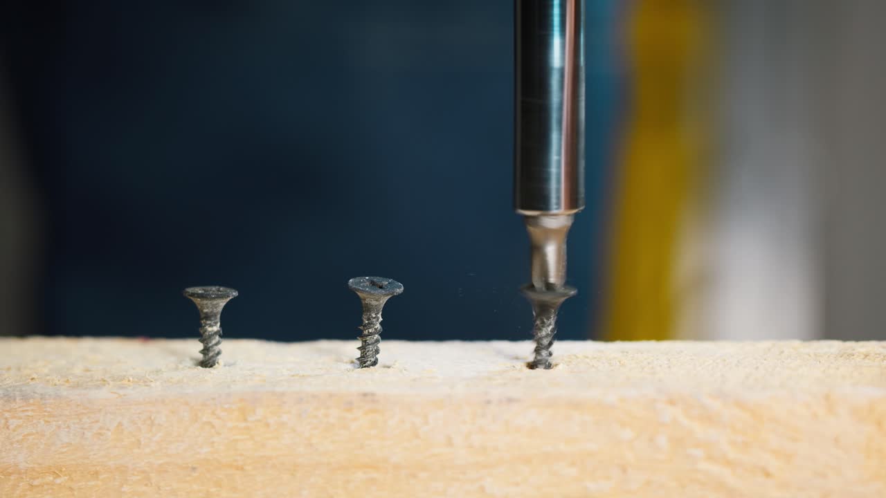 Primo piano di un trapano avvitatore che avvita viti in una tavola di legno