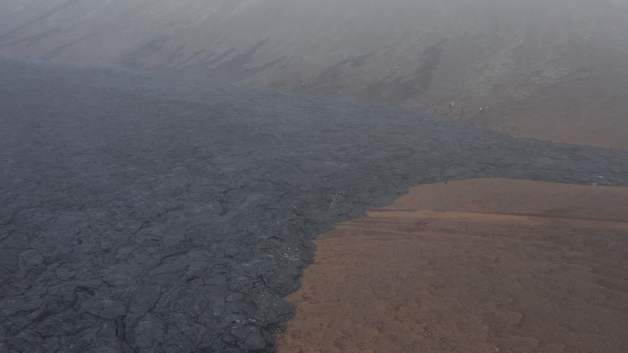 Foggy scenery in valley with dark black basalt rock from eruption