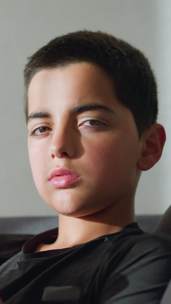 Boy holding tea cup close to mouth, staring at camera, looking tired and sick, with soft light reflecting on his face as he gently closes and opens his eyes in a moment of contemplation