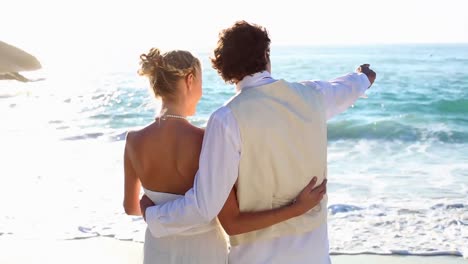 recién casados riendo y mirando hacia el mar