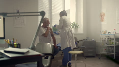 especialista médico inyectando la vacuna en el hombro de un paciente anciano en el hospital.