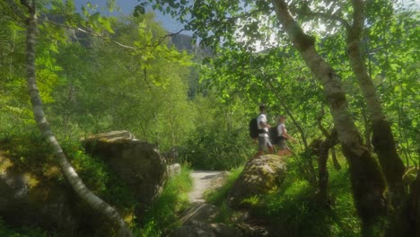 husband and wife backpacking in green landscape of norway, static view