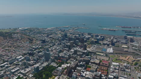 Vista-De-ángulo-Alto-De-La-Ciudad-En-La-Costa-Del-Mar.-Edificios-Altos-En-El-Centro-De-La-Ciudad,-La-Estación-De-Tren-Y-El-Puerto.-Ciudad-Del-Cabo,-Sudáfrica