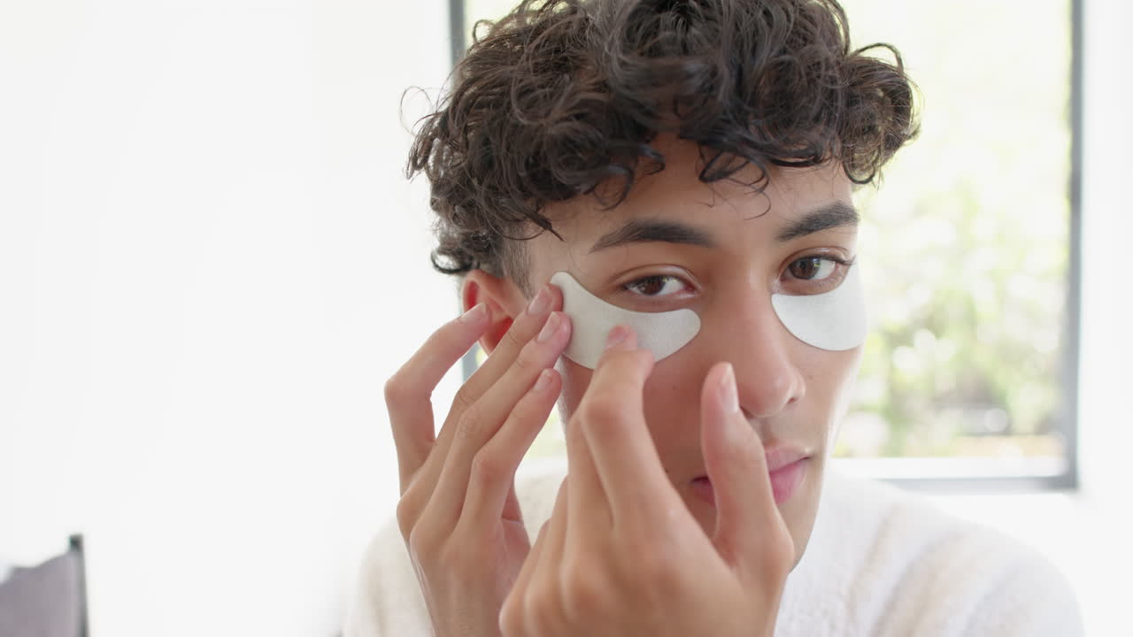 Applying under-eye patches, person focusing on skincare routine at home