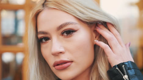 portrait of pretty young blonde woman in with makeup lips and manicure looking at camera