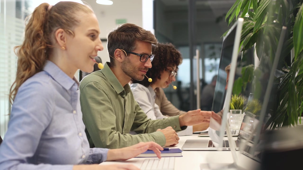 Diverse Team of Call Center Agents Working and Communicating in Office