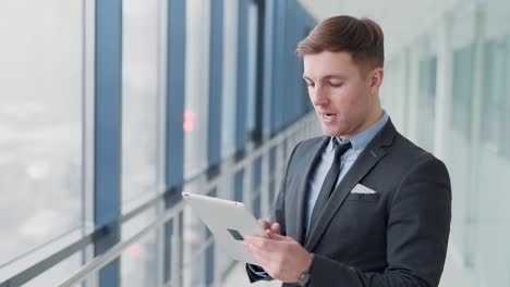 Geschäftsmann-Im-Flur-Des-Business-Centers-Mit-Blick-Auf-Tablet