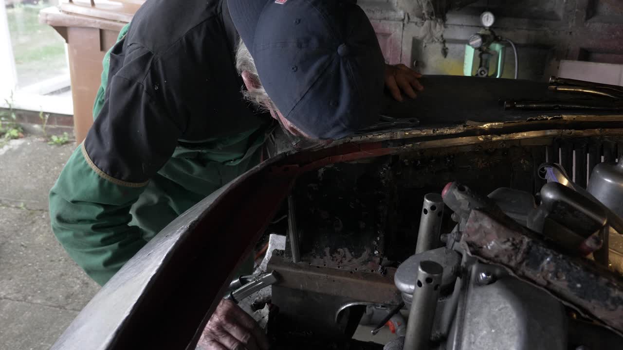 mecánico de vista bloqueada comprobando el trabajo de la carrocería delantera en el coche