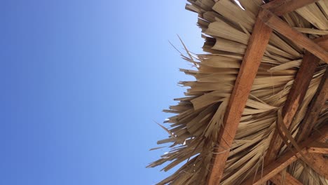 paraguas de playa de paja en una ligera brisa, vacaciones bajo un cielo azul