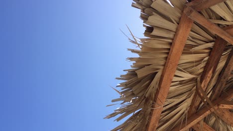 straw beach umbrella in slight breeze, vacation under blue sky