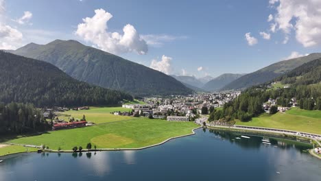 colorful aerial view over the lake with davos residential area in the background, surrounded by rolling hills in kanton graubünden, switzerland