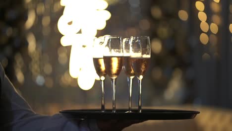 butler holding and serving a tray with champagne glasses in a glamorous lighted environment