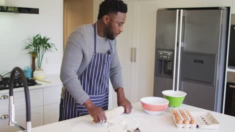 focused african american man using flour, preparing dough in kitchen
