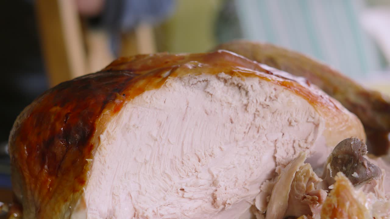 Turkey Being Carved at Dinner Table and Served onto Plates with Crispy Skin and White Meat. Traditional Food Served at Thanksgiving or Christmas.