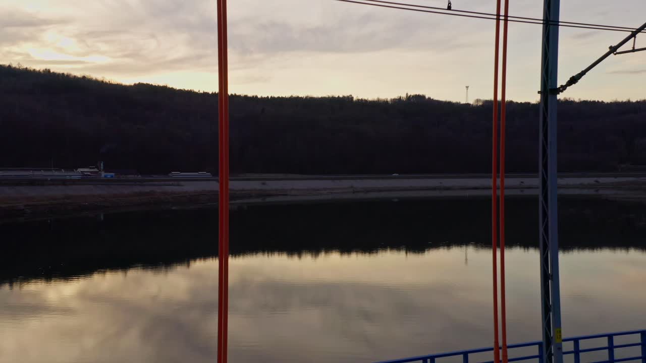 el cielo y los árboles se reflejan en el agua, el dron revela el puente del arco del ferrocarril al atardecer