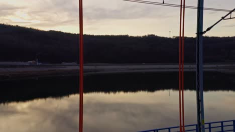 sky and trees reflecting on the water, drone reveal the railroad arch bridge at dusk