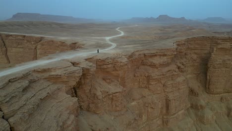 person standing on cliff edge at edge of the world in saudi arabia