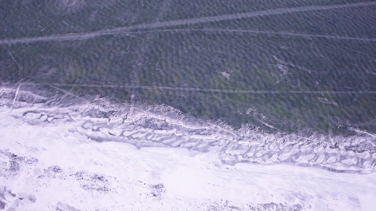 Cinematic top-down drone shot of frozen lake surface and ice textures