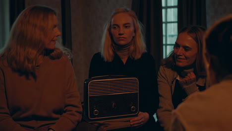 group gathering around a vintage radio in a dimly lit room