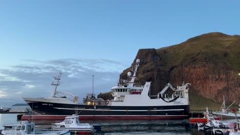 ships in harbor at heimaey island of vestmannaeyjar in iceland with cliff in background