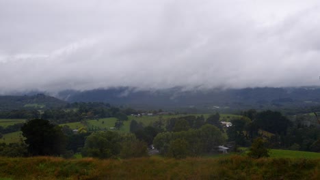 a slow time lapse of misty rainy white clouds rolling across a rural landscape in australia during the winter