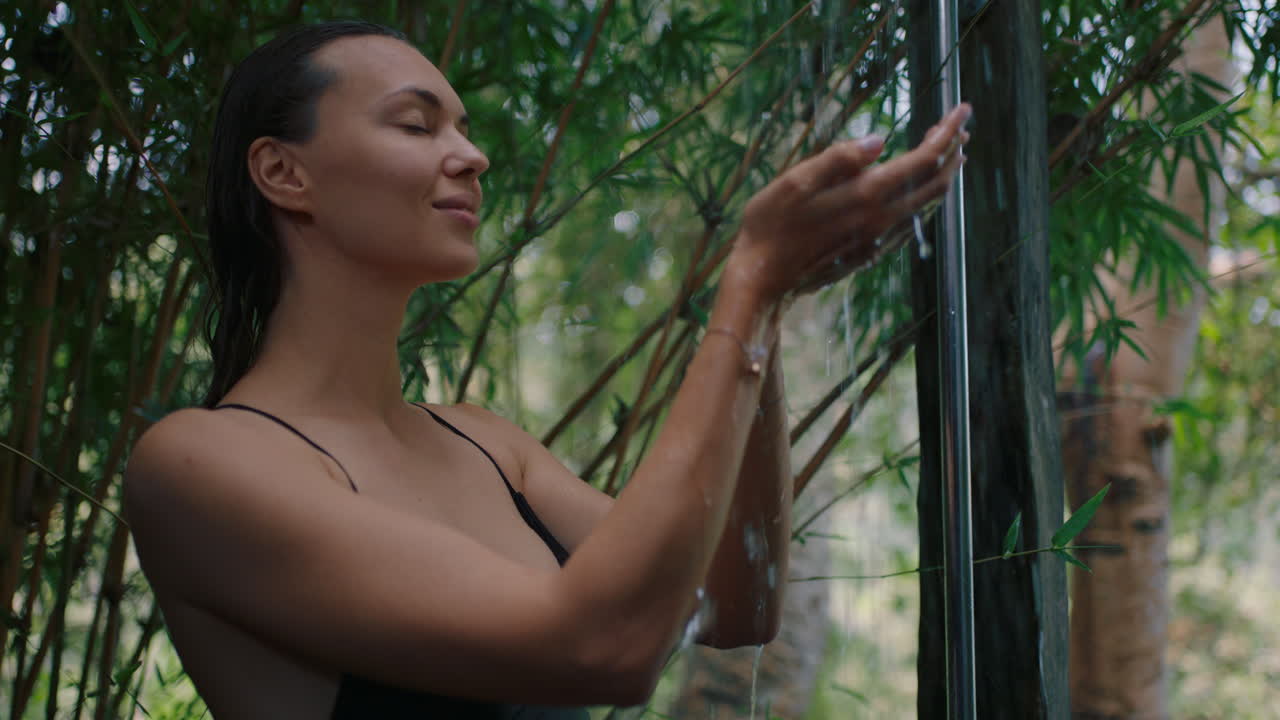 hermosa mujer en la ducha atrapando agua en las manos disfrutando de una limpieza refrescante duchándose al aire libre en la naturaleza