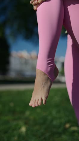woman practicing yoga or exercise in park wearing pink leggings