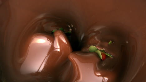 strawberries falling into melted chocolate