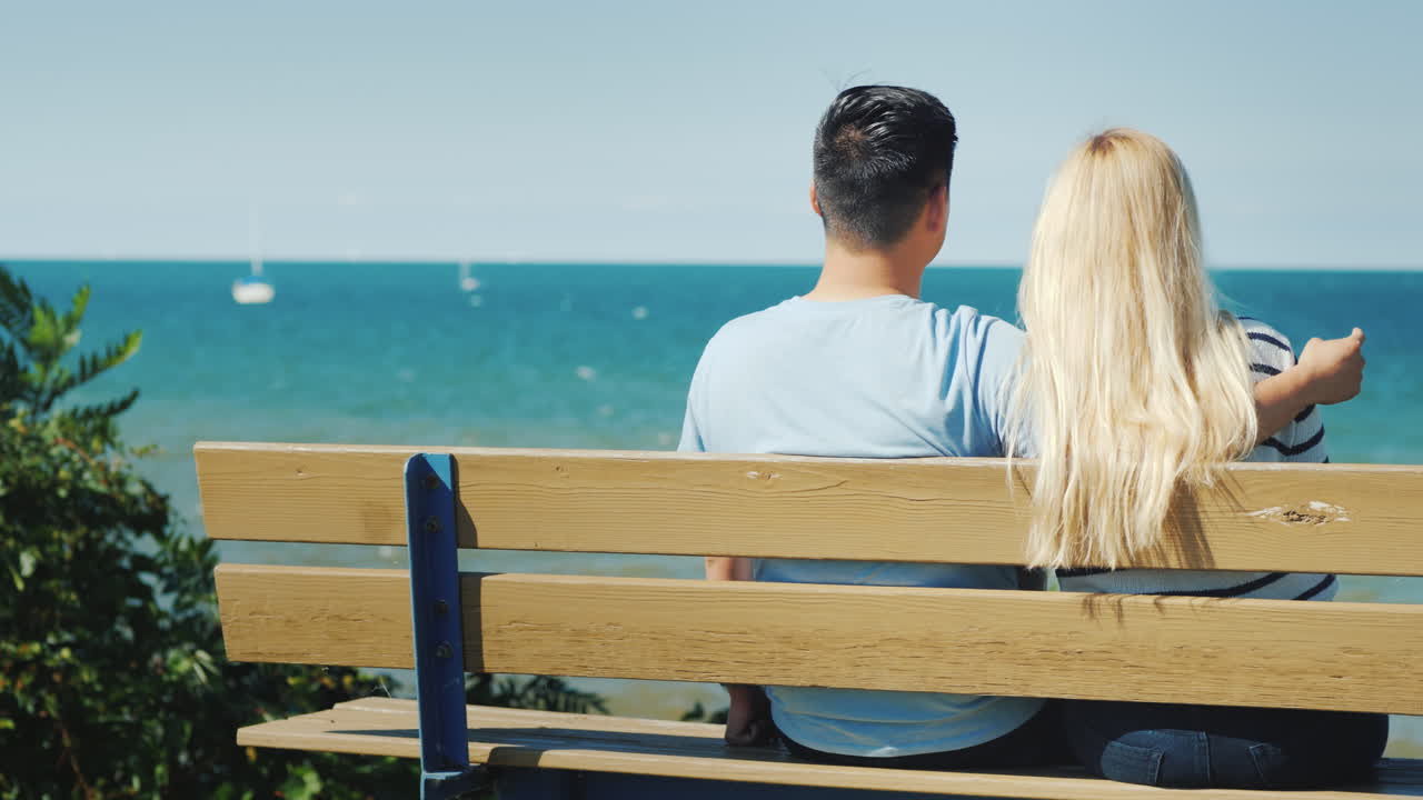 온타리오 호수가 내려다보이는 벤치에서 쉬고 있는 젊은 다민족 부부