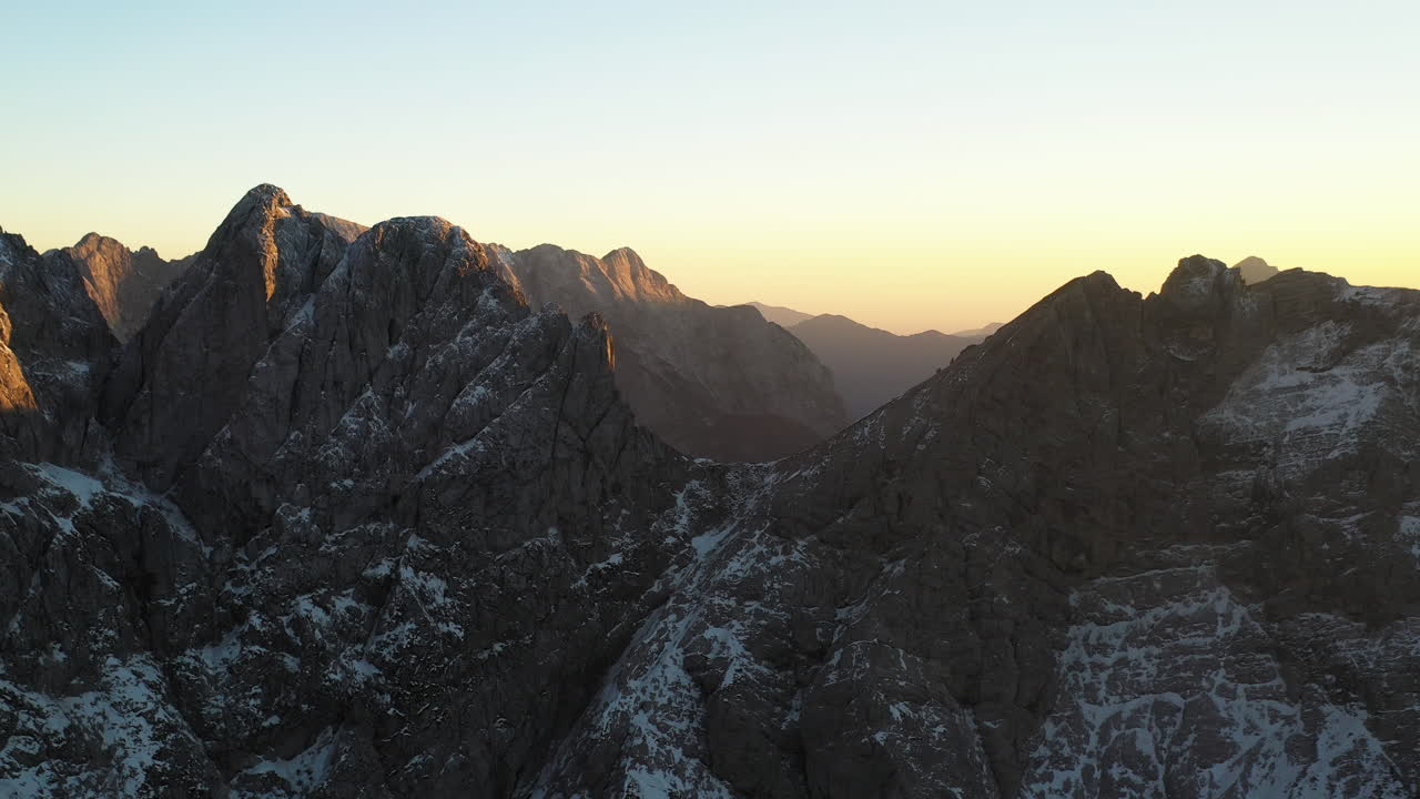 Cinematic drone shot of the Julian Alps of Slovenia, with snow covered peaks
