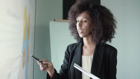 mujer de negocios afroamericana sosteniendo un bolígrafo y señalando el mapa