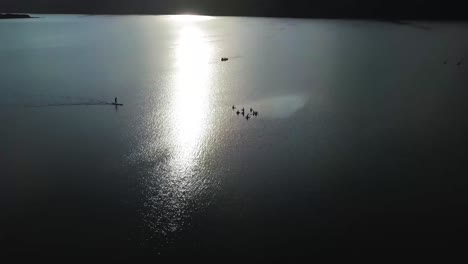 aerial sot of group of people in the sea while camera moves away