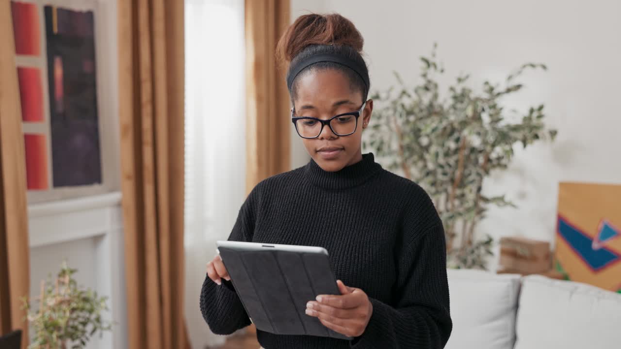 Smiling attractive girl orders furniture online for new apartment, decorates home after move, looks for decorating inspiration, evaluates how it will look in her home, uses tablet