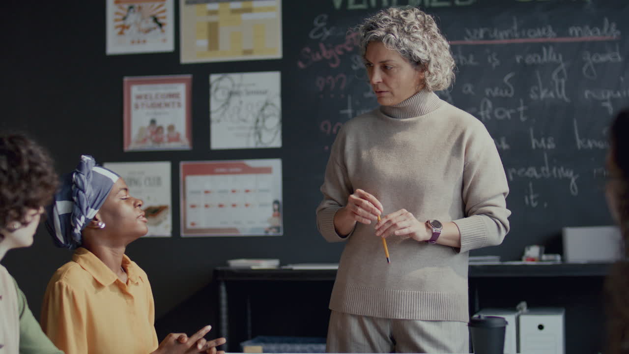 grupo de estudiantes discutiendo el tema de la lección de inglés con una maestra